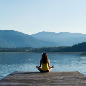 women mediating at the lake looking at mountains