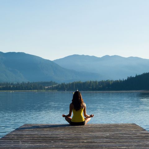 women mediating at the lake looking at mountains